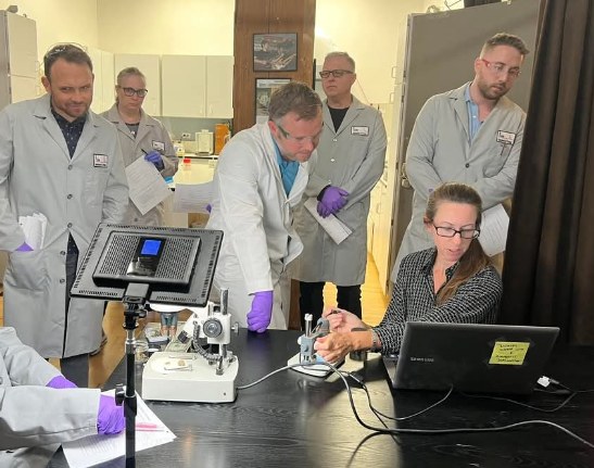 Attorneys gathered around an instrument during a hands-on bench demonstration at Axion Analytical Labs