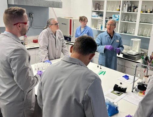 Dr. Lee Polite in a lab coat teaching attorneys at the laboratory bench with analytical instruments
