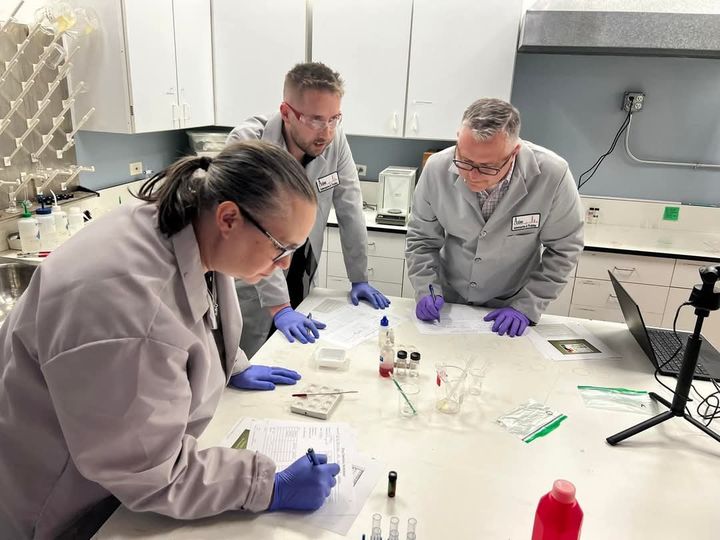 Attorneys in Axion lab coats preparing and analyzing samples at a laboratory bench